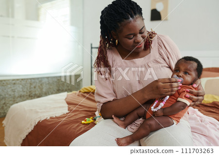 Mother giving pacifier to newborn baby and rocking to sleep Mother giving pacifier to newborn baby and rocking to sleep 111703263