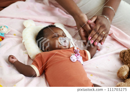 Mother touching hand of sleeping newborn baby Mother touching hand of sleeping newborn baby 111703275