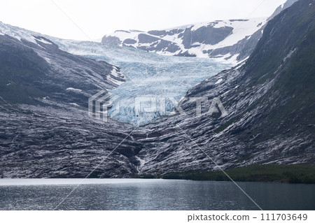 Serene lake at Svartisen Glacier's base mirrors the twilight in Arctic wilderness's embrace 111703649