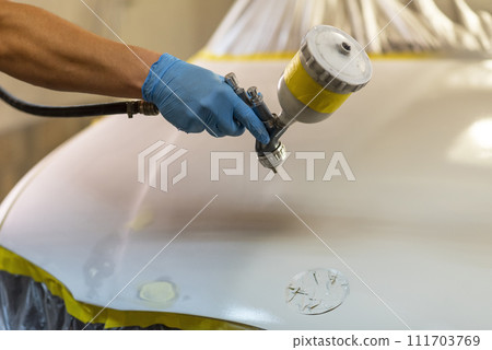 Man with protective clothes and mask painting car using spray compressor. Selective focus. 111703769