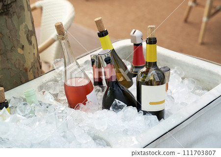 Different wine bottles set in ice bucket on a summer terrace of a restaurant. Different wine bottles set in ice bucket on a summer terrace of a restaurant. 111703807