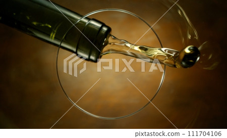Freeze Motion Shot of White Wine Pouring, Unique Angle of View from the Bottom of the Glass 111704106