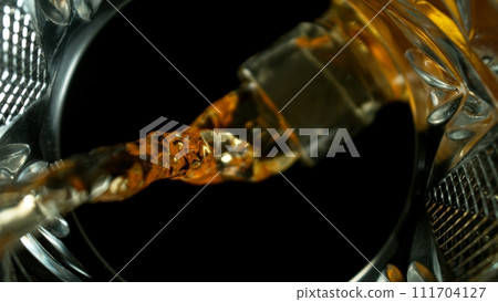Freeze Motion Shot of Whiskey Liquid Pouring, Macro, Unique Angle of View from the Bottom of the Glass Freeze Motion Shot of Whiskey Liquid Pouring, Macro, Unique Angle of View from the Bottom of the Glass 111704127
