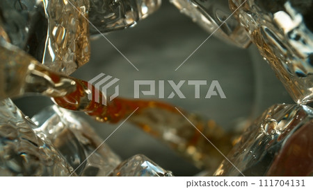 Freeze Motion Shot of Whiskey Liquid Pouring, Macro, Unique Angle of View from the Bottom of the Glass Freeze Motion Shot of Whiskey Liquid Pouring, Macro, Unique Angle of View from the Bottom of the Glass 111704131