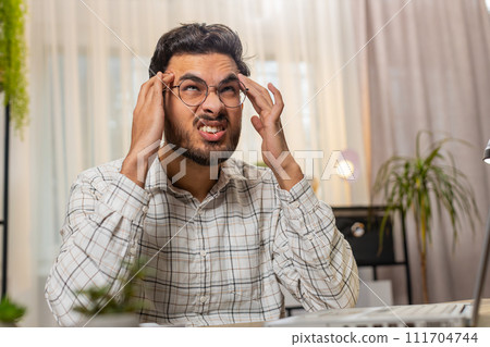 Tired ill Indian businessman suffering from headache problem tension migraine stress at home office 111704744