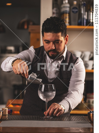 Barman putting ice cubes into glass 111704839
