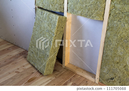 Wooden frame for future walls with drywall plates insulated with rock wool and fiberglass insulation staff for cold barrier. Comfortable warm home, economy, construction and renovation concept. Wooden frame for future walls with drywall plates insulated with rock wool and fiberglass insulation staff for cold barrier. Comfortable warm home, economy, construction and renovation concept. 111705088