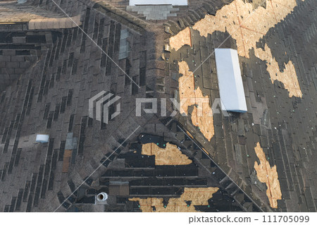 Wind damaged house roof with missing asphalt shingles after hurricane Ian in Florida. Repair of home rooftop concept 111705099