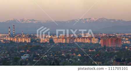 Wide panorama, aerial view of Ivano-Frankivsk city, Ukraine. Scene of modern tourist city with tall buildings, residential quarters and green streets on background of distant Carpathian mountains. 111705101