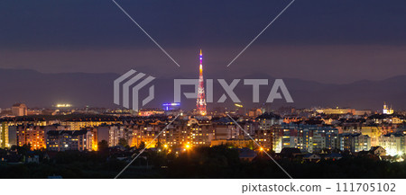 Wide panorama, aerial night view of modern tourist Ivano-Frankivsk city, Ukraine. Scene of bright lights of tall buildings, high television tower and green suburbs on Carpathian mountains background. Wide panorama, aerial night view of modern tourist Ivano-Frankivsk city, Ukraine. Scene of bright lights of tall buildings, high television tower and green suburbs on Carpathian mountains background. 111705102