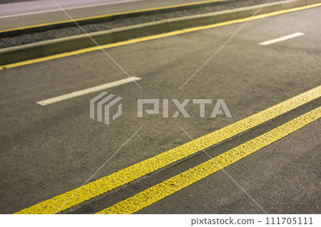 Wide bright yellow street marking sign line along modern wide smooth empty asphalt highway stretching to horizon. Speed, safety, comfortable journey and professional road building concept. 111705111