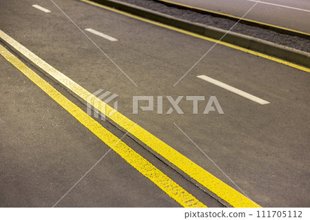 Wide bright double yellow marking sign line along modern wide smooth empty asphalt highway street stretching to horizon. Speed, safety, comfortable journey and professional road building concept. 111705112