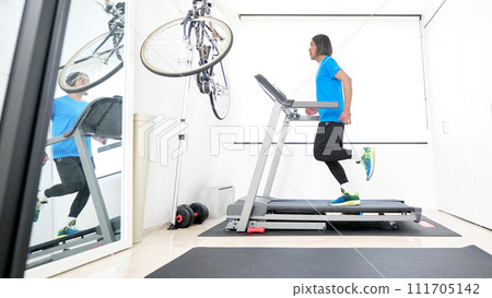 Middle-aged man running on a treadmill Middle-aged man running on a treadmill 111705142