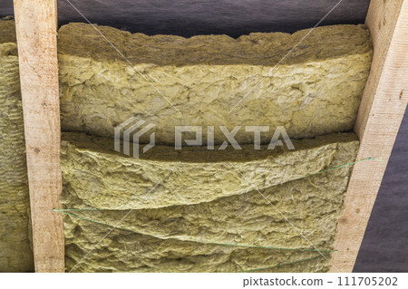 Thermal insulation mineral rock wool installation at the new building attic ceiling Thermal insulation mineral rock wool installation at the new building attic ceiling 111705202