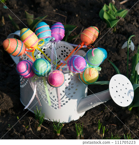 Colorful Easter eggs in a white decorative watering can. 111705223