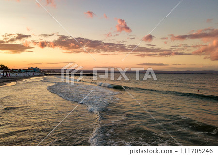 Sea surface with blue water waves under yellow and purple sunset sky. 111705246