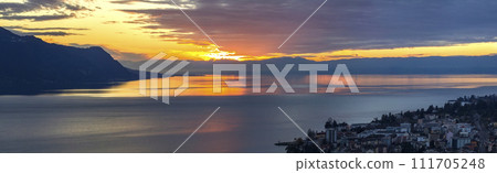 Scenic view of sunset over the Leman lake with yellow sky with clouds and Alps mountains in background, Montreux, Switzerland. 111705248