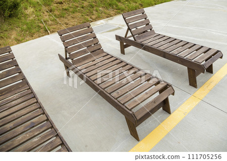 Row of empty wooden beach chairs near water outdoors. Row of empty wooden beach chairs near water outdoors. 111705256