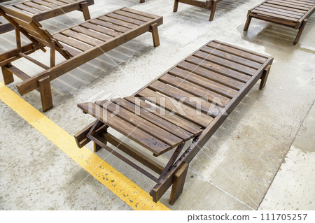Row of empty wooden beach chairs near water outdoors. 111705257