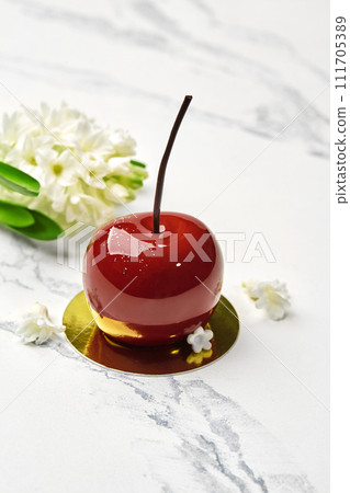 Tempting cherry-shaped pastry with white flowers on marble 111705389