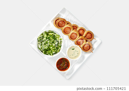 Hearty breakfast with baked sausage rolls, salad, and dipping sauces 111705421
