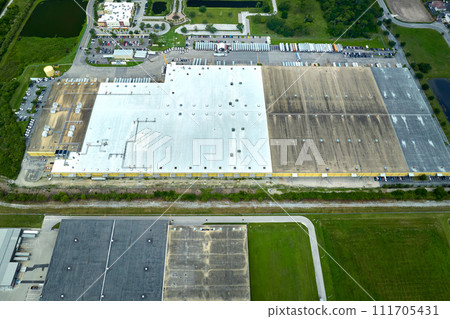 Large commercial distribution storehouse with many semitrucks unloading and uploading retail products for international shipment. Global market economy concept Large commercial distribution storehouse with many semitrucks unloading and uploading retail products for international shipment. Global market economy concept 111705431