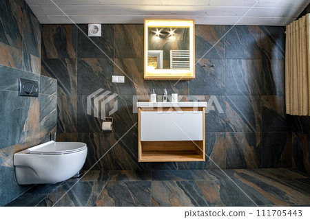 Interior of modern stylish bathroom with black tiled walls, curtain shower place and wooden furniture with wash basin and big illuminated mirror. Interior of modern stylish bathroom with black tiled walls, curtain shower place and wooden furniture with wash basin and big illuminated mirror. 111705443