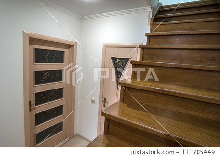 Interior of a house or appartment hallway with oak wooden stairs and room doors. Interior of a house or appartment hallway with oak wooden stairs and room doors. 111705449