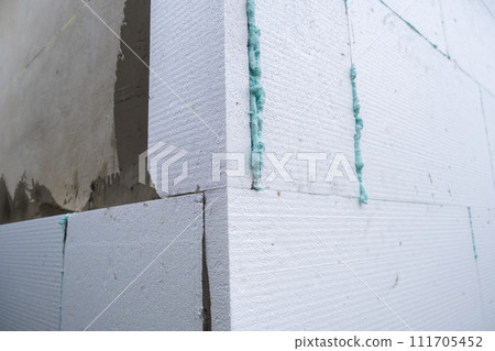 Installation of styrofoam insulation sheets on house facade wall for thermal protection. 111705452