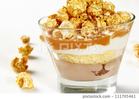 Glass of layered caramel popcorn dessert with sponge cake Glass of layered caramel popcorn dessert with sponge cake 111705461