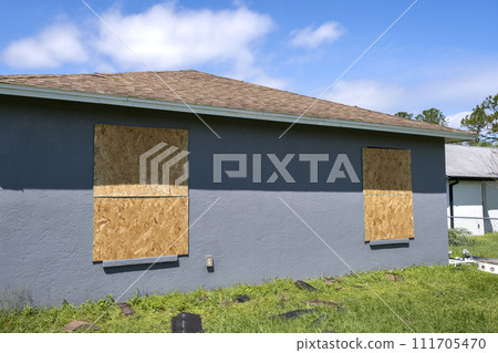 Hurricane shutters made from plywood mounted for protection of house windows. Protective measures before natural disaster in Florida Hurricane shutters made from plywood mounted for protection of house windows. Protective measures before natural disaster in Florida 111705470