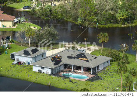 Hurricane Ian destroyed house with damaged roof and lanai enclosure over swimming pool in Florida residential area. Consequences of natural disaster 111705471