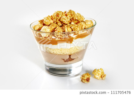 Layered trifle with sponge cake, caramel sauce and popcorn in glass Layered trifle with sponge cake, caramel sauce and popcorn in glass 111705476