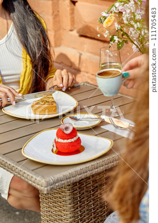 Women enjoying savory pie and sweet pastry in outdoor cafe 111705483