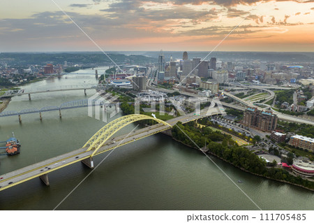 Highway traffic in Cincinnati, Ohio on Daniel Carter Beard Bridge with brightly illuminated high skyscraper buildings in downtown district. American city with business financial district at sunset 111705485