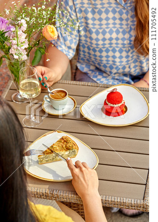 Females enjoying savory tart and sweet dessert at outdoor cafe 111705492