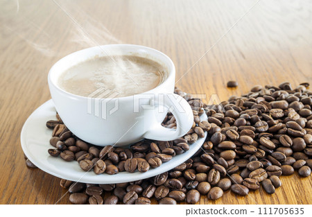 Cup of coffee in a white cup and coffee beans on wooden table ba Cup of coffee in a white cup and coffee beans on wooden table ba 111705635