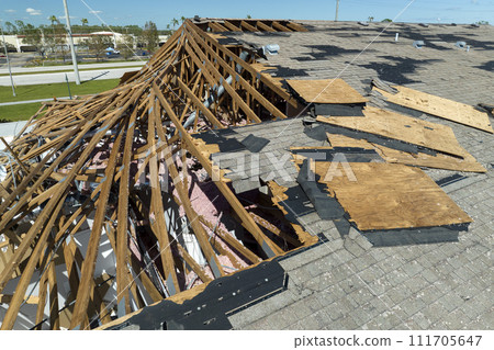 Consequences of natural disaster. Damaged house roof with missing shingles after hurricane Ian in Florida Consequences of natural disaster. Damaged house roof with missing shingles after hurricane Ian in Florida 111705647