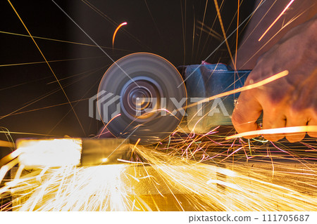 Close-up of worker hands cutting metal with grinder. Sparks while grinding iron. Low depth of focus Close-up of worker hands cutting metal with grinder. Sparks while grinding iron. Low depth of focus 111705687