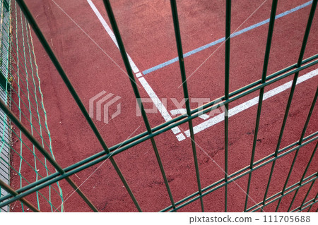 Close-up of white marking lines of outdoor basketball court fenced with protective metal fence. 111705688