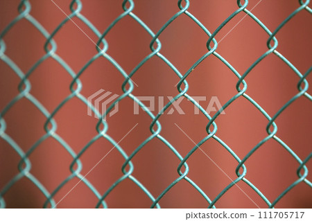 Close-up of isolated painted simple geometric black iron metal wire chain link fence eon dark red background. Fence, protection and enclosure concept. Close-up of isolated painted simple geometric black iron metal wire chain link fence eon dark red background. Fence, protection and enclosure concept. 111705717