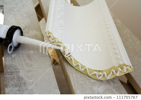 Close-up detail of decoration molding with glue adhesive before installation in interior renovation. 111705767