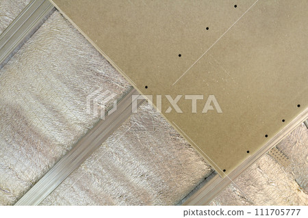 Room under construction with silver aluminum insulation foil and drywall on walls and ceiling. 111705777
