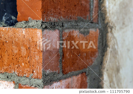 Close up of bricklaying industrial installing bricks on construction site wall Close up of bricklaying industrial installing bricks on construction site wall 111705790