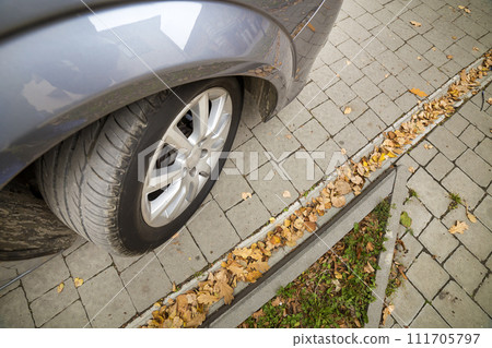 Close up detail part of car wheel with new black rubber tire protector on sunny pavement background. Transportation, safety, reliability, modern design concept. 111705797