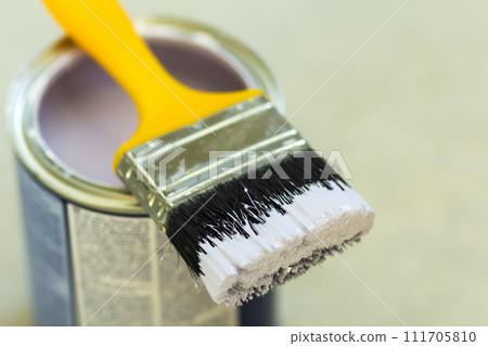 Can of white paint with paint brush over grey background. Shallow depth of field effect Can of white paint with paint brush over grey background. Shallow depth of field effect 111705810
