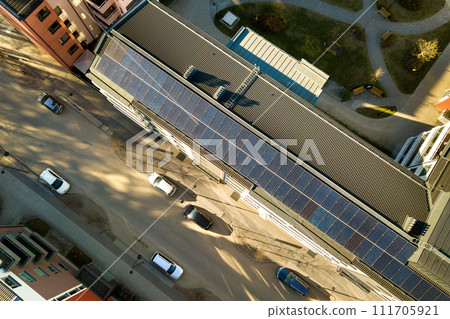 Aerial view of solar photovoltaic panels on a roof top of residential building block for producing clean electric energy. Autonomous housing concept. Aerial view of solar photovoltaic panels on a roof top of residential building block for producing clean electric energy. Autonomous housing concept. 111705921