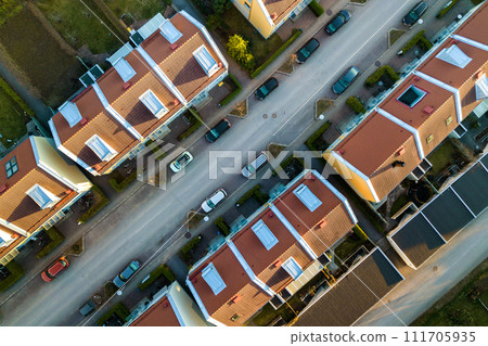 Aerial view of residential houses with red roofs and streets with parked cars in rural town area. Quiet suburbs of a modern european city. 111705935