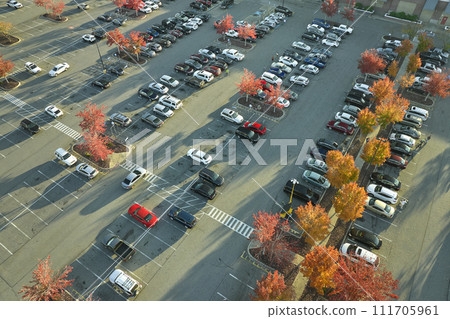 Aerial view of large parking lot with many parked colorful cars. Carpark at supercenter shopping mall with lines and markings for vehicle places and directions Aerial view of large parking lot with many parked colorful cars. Carpark at supercenter shopping mall with lines and markings for vehicle places and directions 111705961