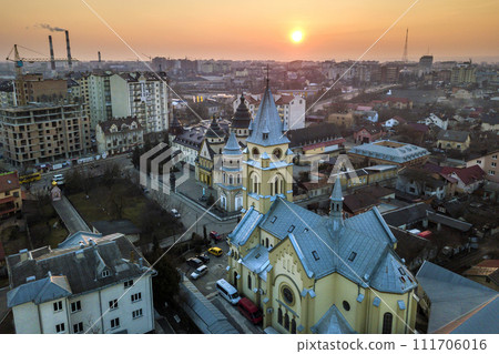 Aerial view of city at dawn or dusk. Urban landscape with church domes, parked cars, high buildings on bright pink sky at sunset background. Aerial view of city at dawn or dusk. Urban landscape with church domes, parked cars, high buildings on bright pink sky at sunset background. 111706016